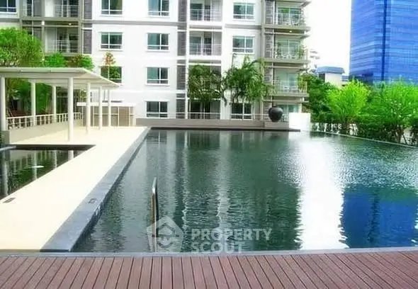 Luxurious apartment complex with serene pool and modern architecture.