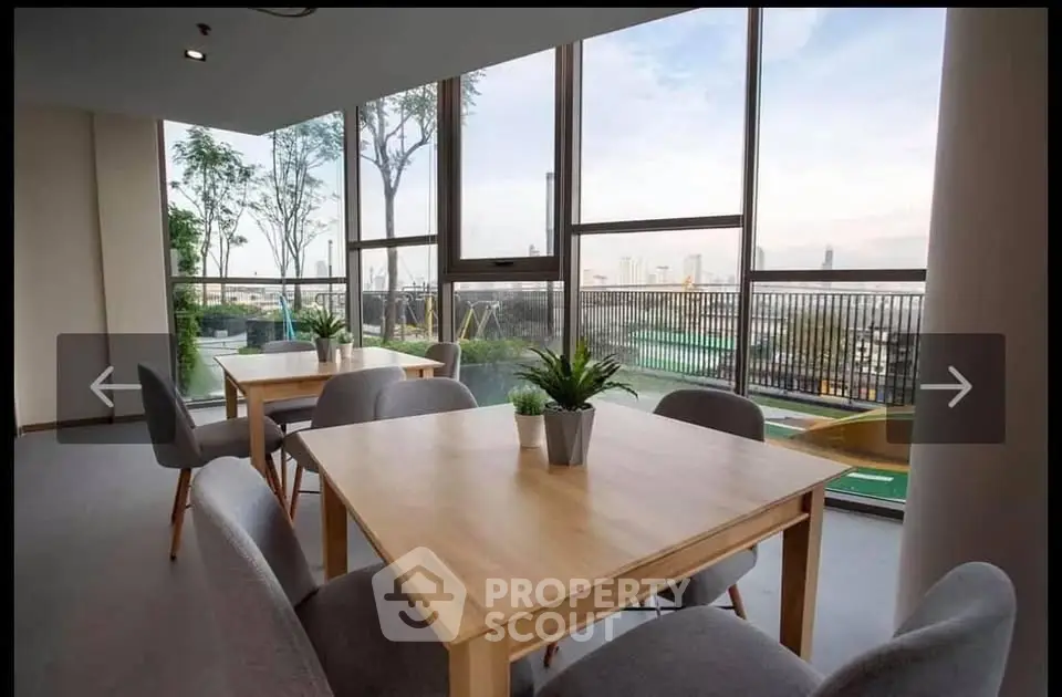 Modern communal area with large windows and city view, featuring stylish tables and chairs.