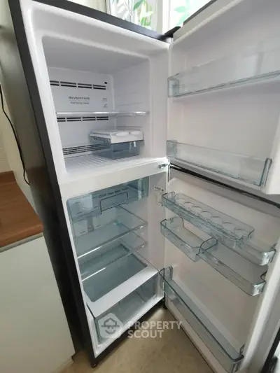 Modern kitchen with open refrigerator showcasing spacious interior and sleek design.