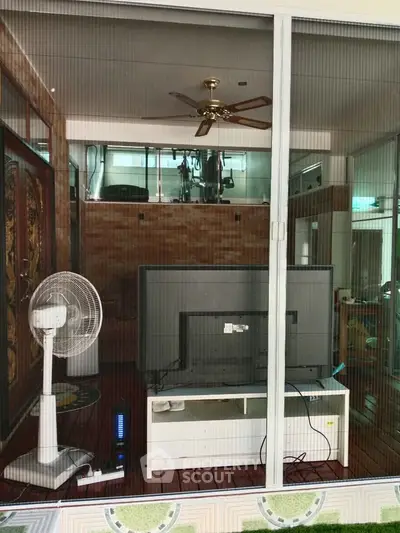 Modern living room with ceiling fan and TV, featuring a stylish interior design.