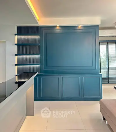 Modern living room with stylish blue accent wall and sleek shelving, featuring contemporary design elements.