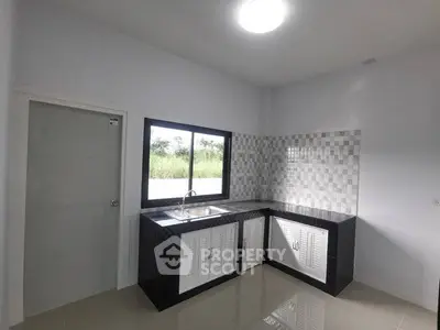 Modern kitchen with sleek black and white design and large window view.