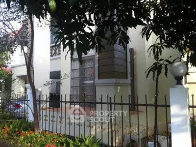 Charming residential exterior with lush garden and elegant fence, perfect for serene living.
