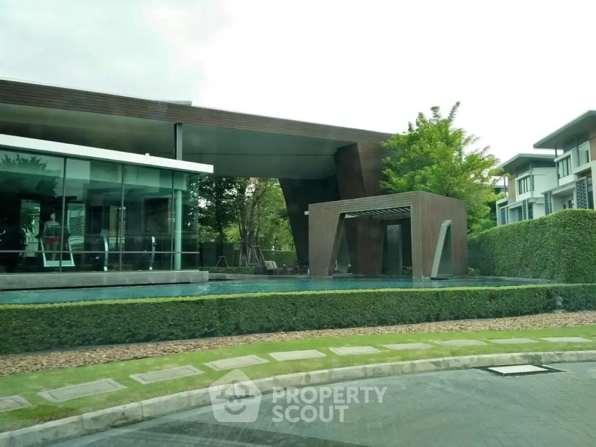 Modern architectural building with sleek design and lush greenery, featuring a stylish pool area.