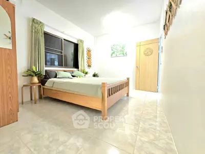 Bright and airy bedroom with wooden bed and green accents, perfect for relaxation.