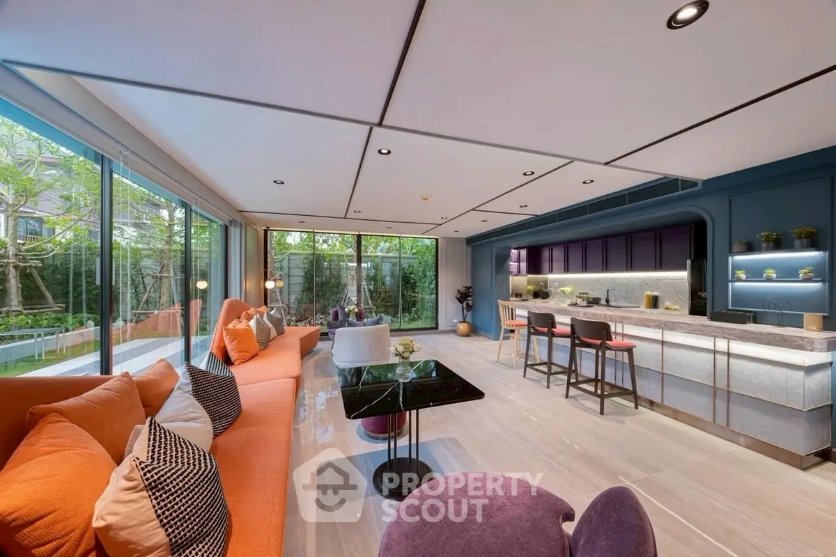 Luxurious open-plan living room with modern kitchen and garden view, featuring stylish furniture and elegant decor.