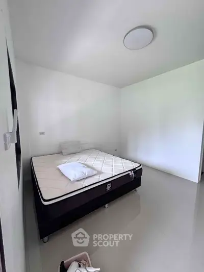 Minimalist bedroom with a simple bed and white walls, perfect for a cozy retreat.