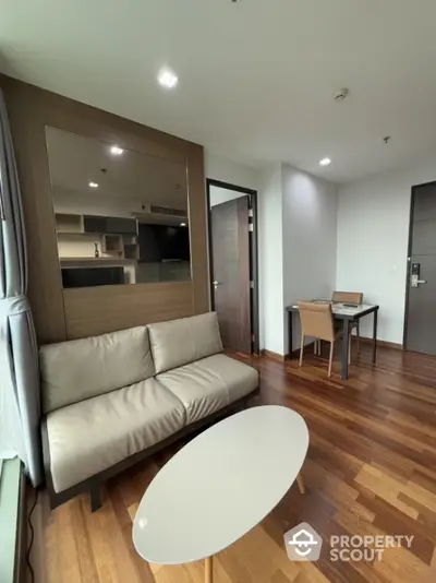 Modern living room with wooden flooring and sleek furniture in a stylish apartment.