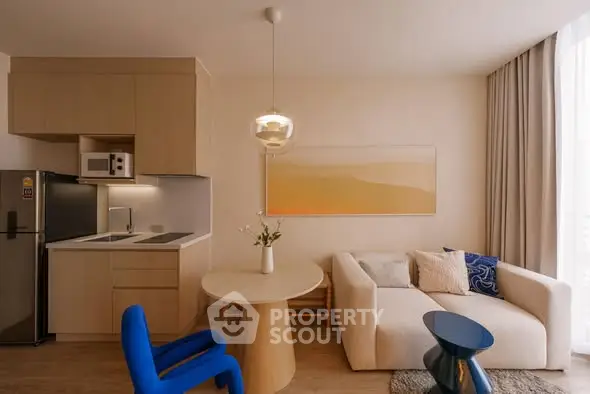 Modern living room with open kitchen, stylish furniture, and natural light.