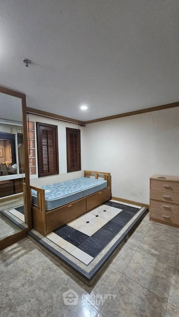Spacious bedroom with wooden furniture and large mirror for modern living.