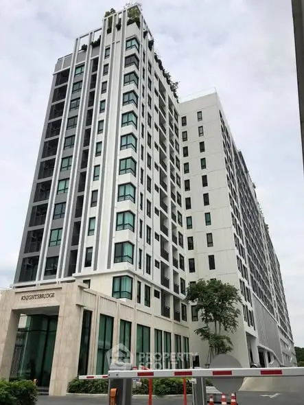 Modern high-rise building with sleek design and lush greenery on rooftop, ideal for urban living.