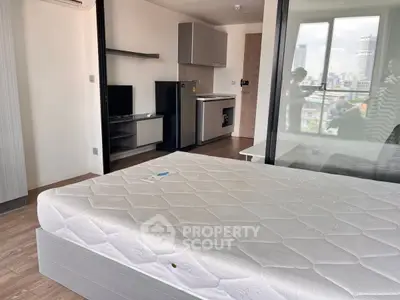 Modern studio apartment with city view, featuring a compact kitchen and cozy living space.