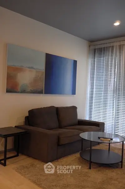Cozy living room with modern sofa, abstract art, and natural light through blinds.