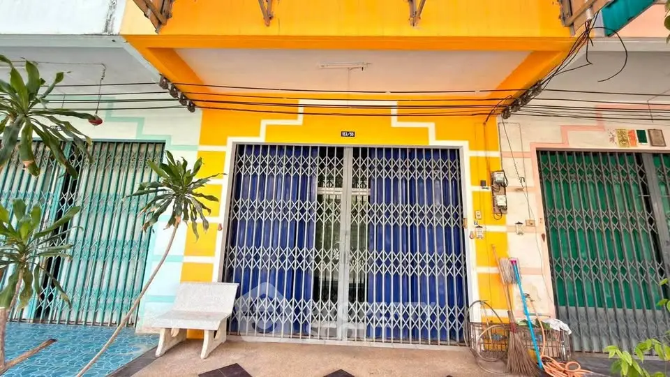 Vibrant yellow exterior of a townhouse with secure metal gate and colorful facade.