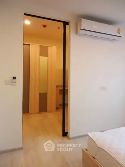 Modern bedroom with air conditioning and wooden flooring, featuring a sliding door to a closet area.