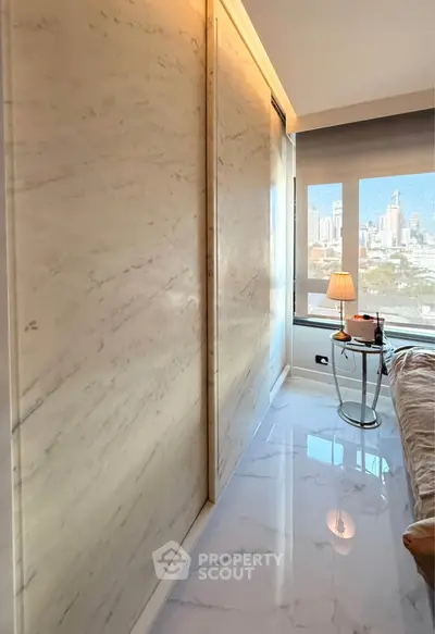 Luxurious bedroom with marble walls and city view, featuring elegant decor and natural light.
