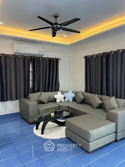 Modern living room with stylish gray sectional sofa and blue tile flooring.