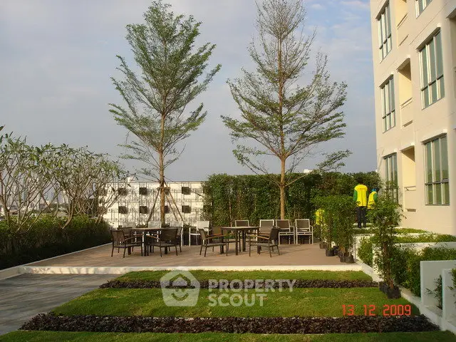 Modern apartment building with landscaped garden and outdoor seating area.