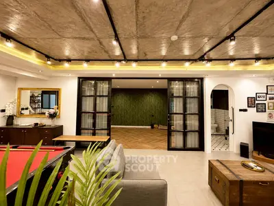 Spacious living room with modern industrial design and pool table, perfect for entertainment.