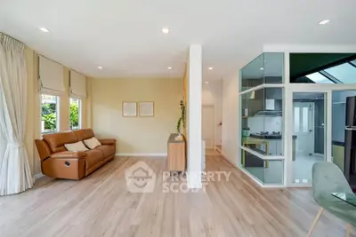 Spacious living room with modern open kitchen, featuring sleek wooden flooring and abundant natural light.
