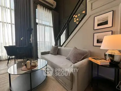 Modern living room with high ceilings, stylish decor, and large windows offering natural light.