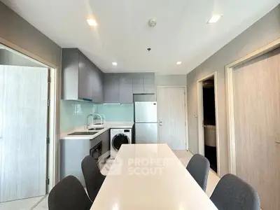 Modern kitchen with sleek cabinetry, dining table, and built-in appliances in a stylish apartment.