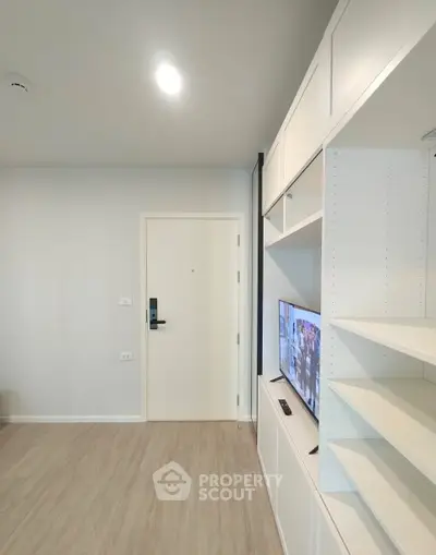 Modern living room with sleek built-in shelving and TV, light wood flooring, and minimalist design.