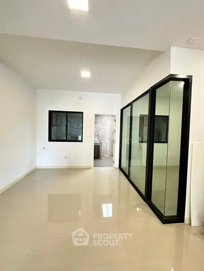 Spacious modern living room with sleek glass partition and polished flooring
