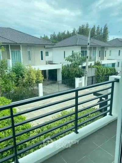 Charming balcony view of modern suburban homes with lush greenery and clear skies.