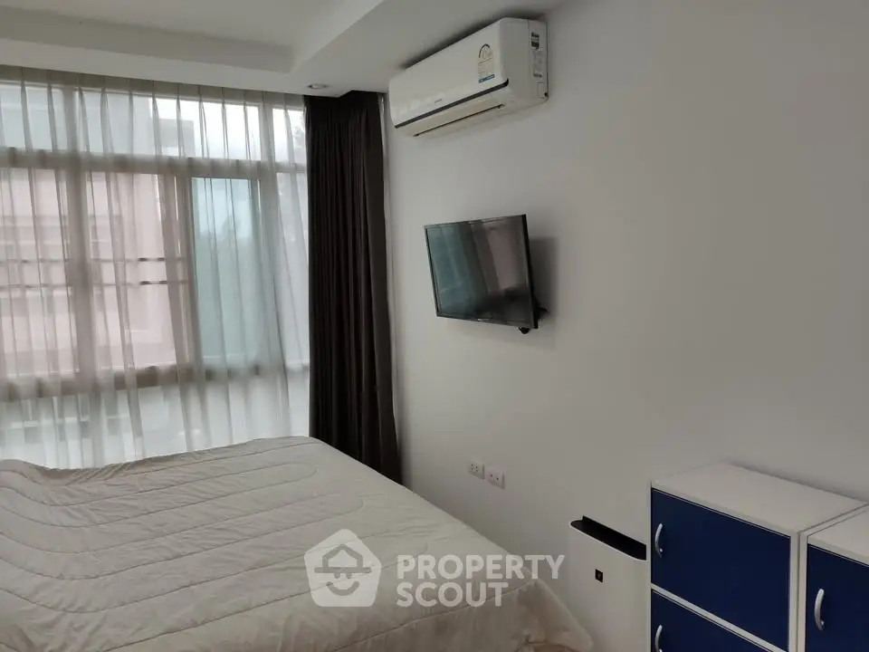Modern bedroom with air conditioning and wall-mounted TV in a bright apartment.