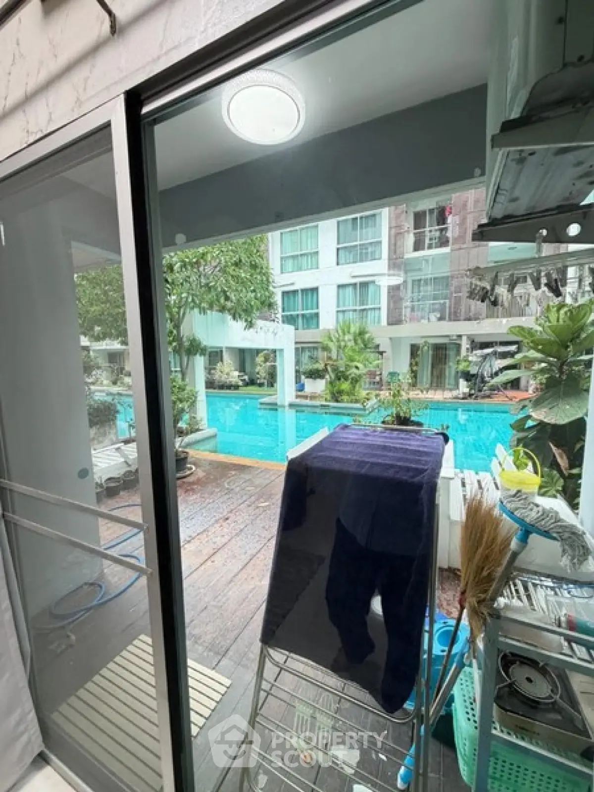 Stunning poolside view from modern apartment with glass doors and lush greenery.
