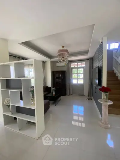 Spacious living room with modern decor and natural light, featuring a stylish partition and elegant staircase.