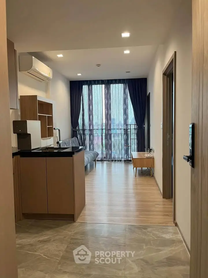 Modern living room with open layout and large windows, featuring stylish furniture and elegant flooring.