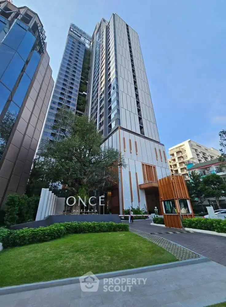 Stunning modern high-rise building with lush green landscaping and sleek architectural design.