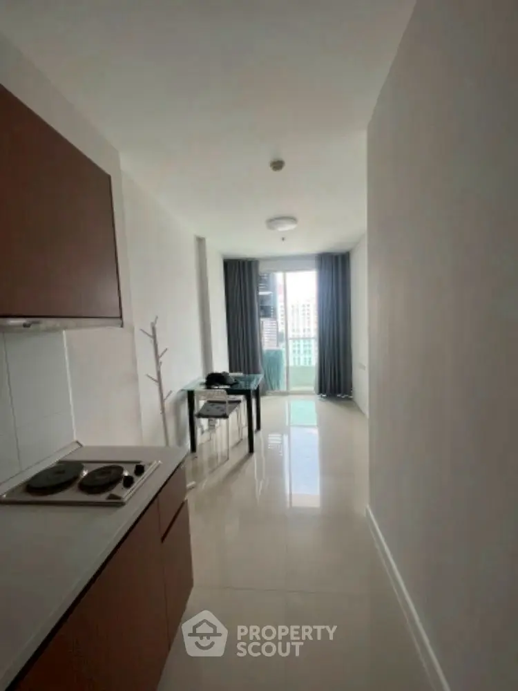 Modern apartment interior with sleek kitchen and city view balcony.