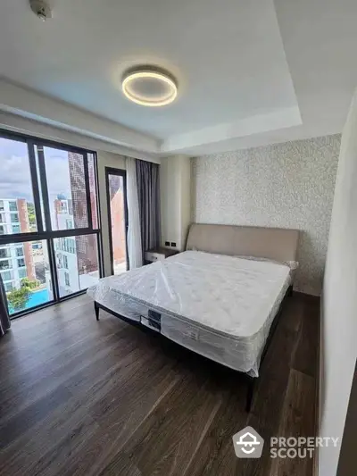 Modern bedroom with large windows and city view, featuring sleek design and natural light.