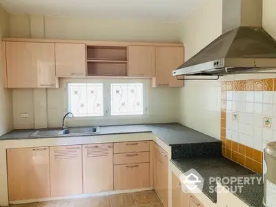 Spacious kitchen with modern cabinetry and stainless steel range hood