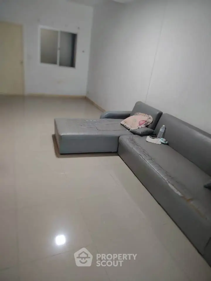 Spacious living room with modern gray sofa and glossy tiled floor.