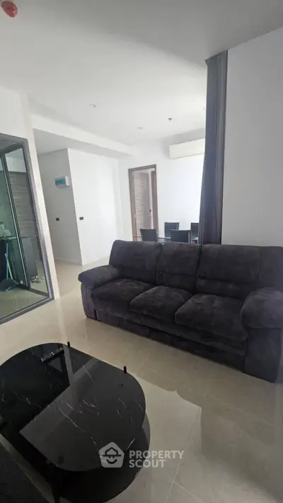 Modern living room with plush sofa and dining area in open layout apartment.