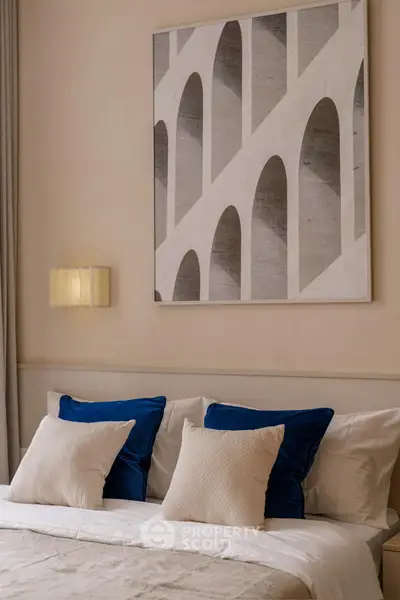 Elegant bedroom with modern art and plush pillows in a cozy setting.