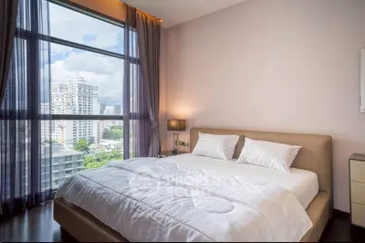 Luxurious bedroom with stunning city view and elegant decor in high-rise apartment.