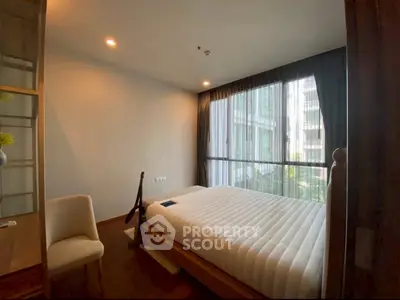 Cozy bedroom with large window and modern furnishings in a stylish apartment.
