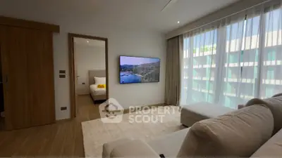 Modern living room with large TV and natural light, adjacent to a cozy bedroom.