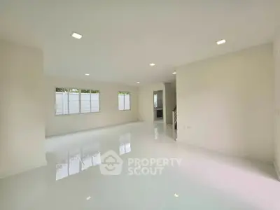 Spacious open-plan living room with glossy white flooring and ample natural light.