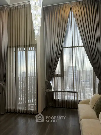 Luxurious living room with floor-to-ceiling windows and elegant drapery offering stunning city views.