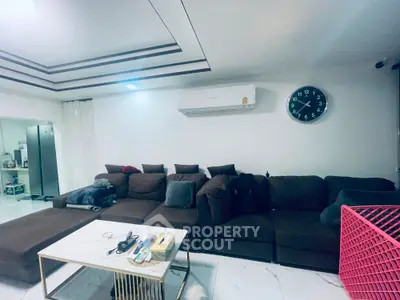 Spacious living room with modern brown sofa and wall-mounted clock, ideal for family gatherings.