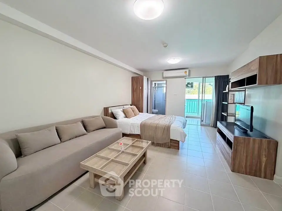 Spacious modern studio apartment with cozy living area and balcony view.