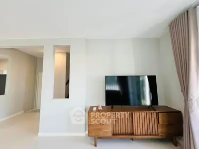 Modern living room with sleek TV stand and large flat-screen TV, elegant curtains, and minimalist decor.