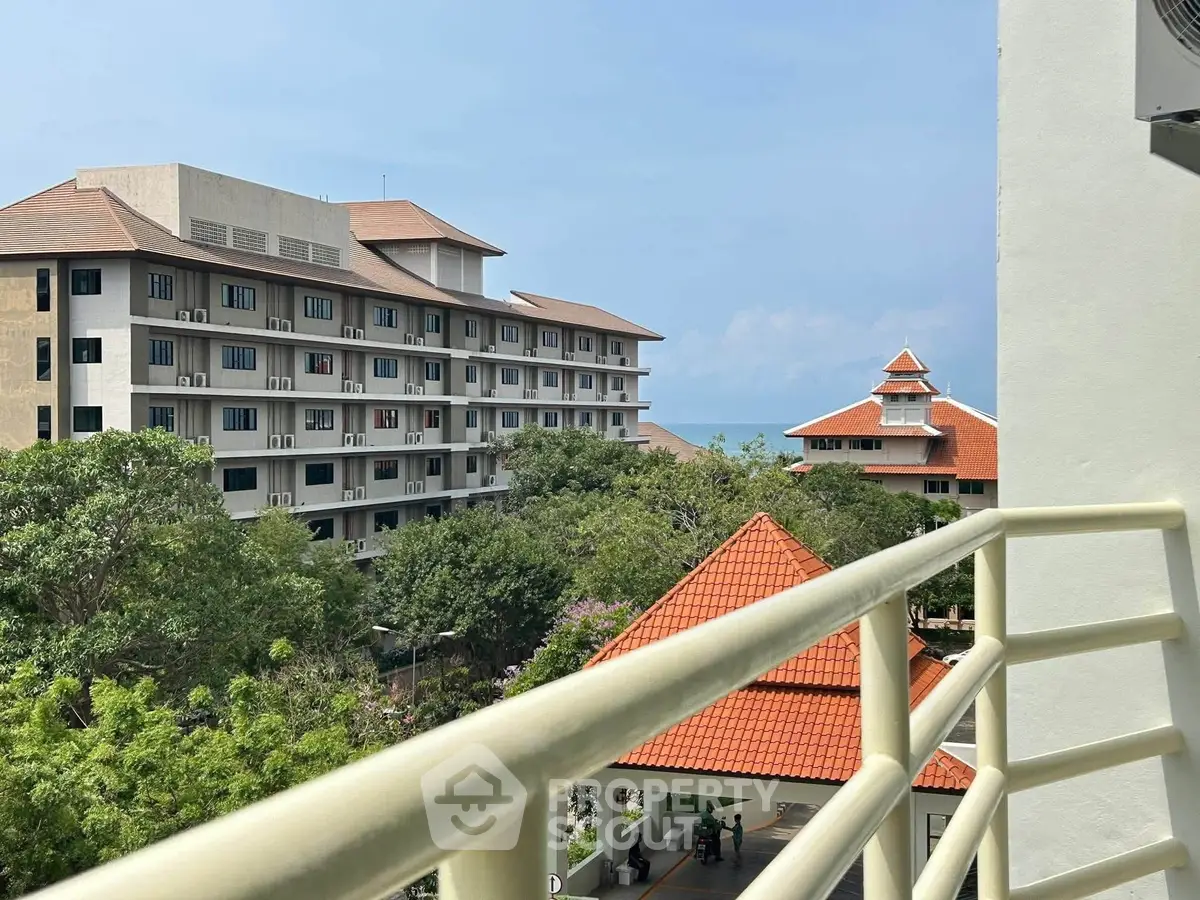 Stunning view from balcony overlooking lush greenery and ocean horizon, perfect for serene living.