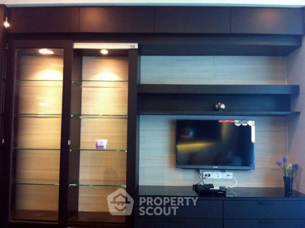 Modern living room with sleek TV unit and glass display shelves.